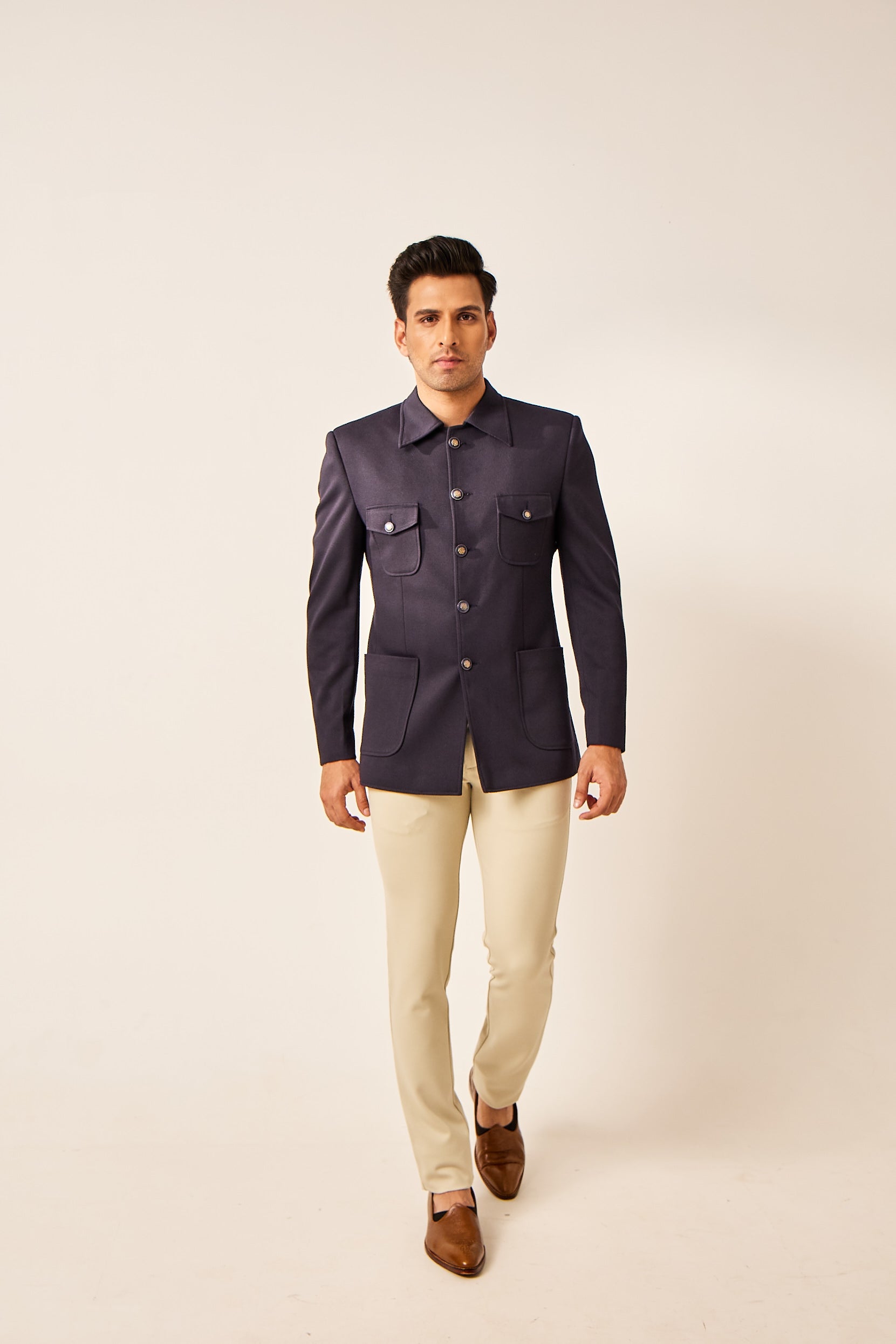 A man poses in a blue lycra blazer with a clean, plain design, elevated by five antique buttons that add a hint of vintage charm.