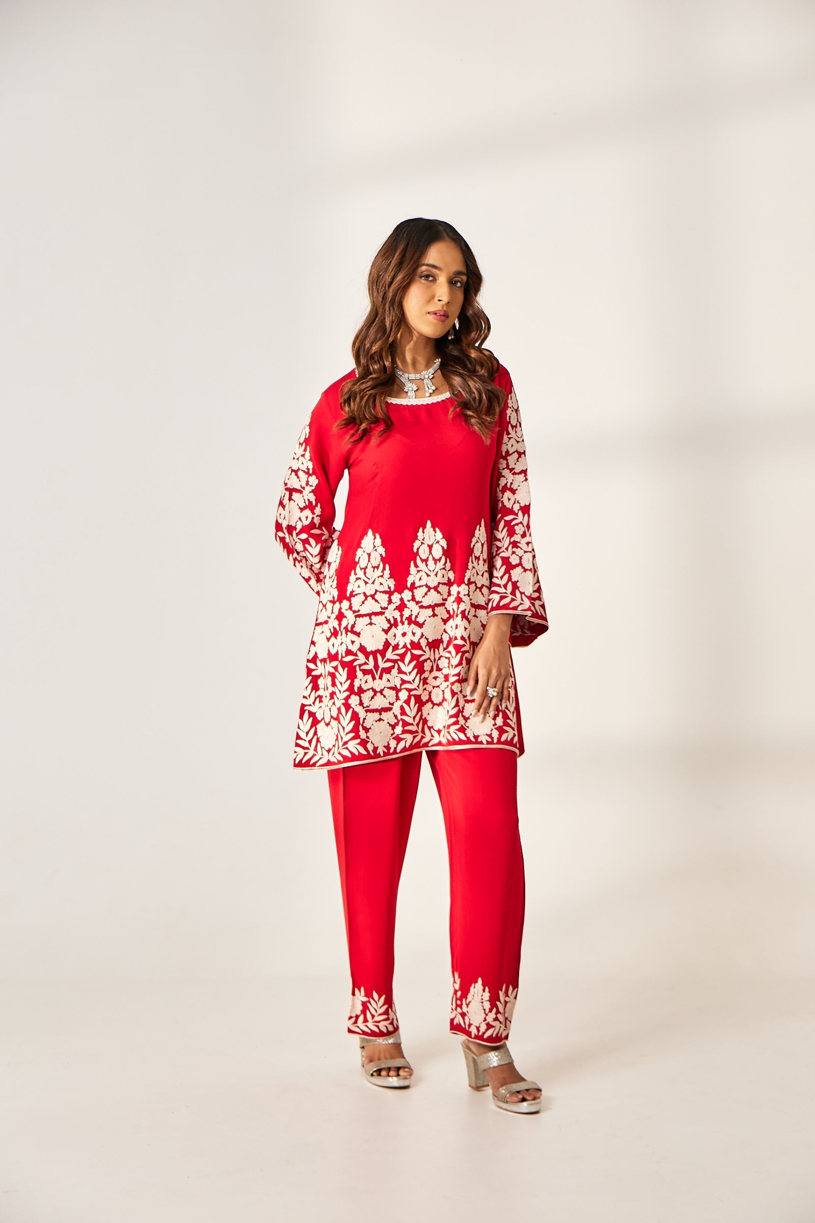 A woman poses in a red co-ord set from BenzerWorld that includes a crepe kurti and georgette pants.
