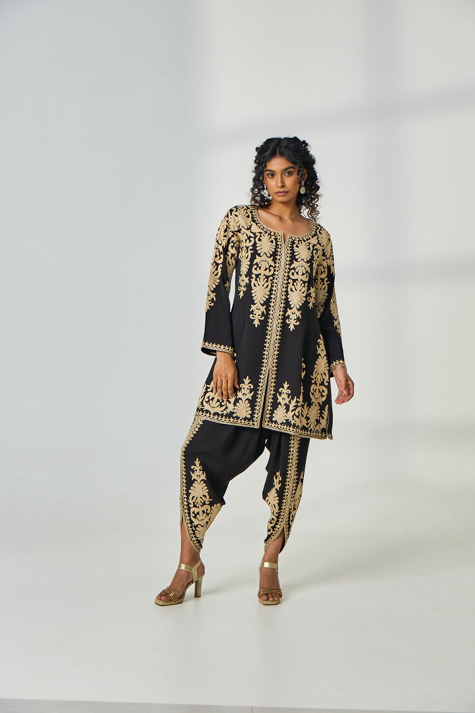 A woman poses in a black crepe co-ord set from BenzerWorld that includes a kurta with resham thread work and dhoti pants.