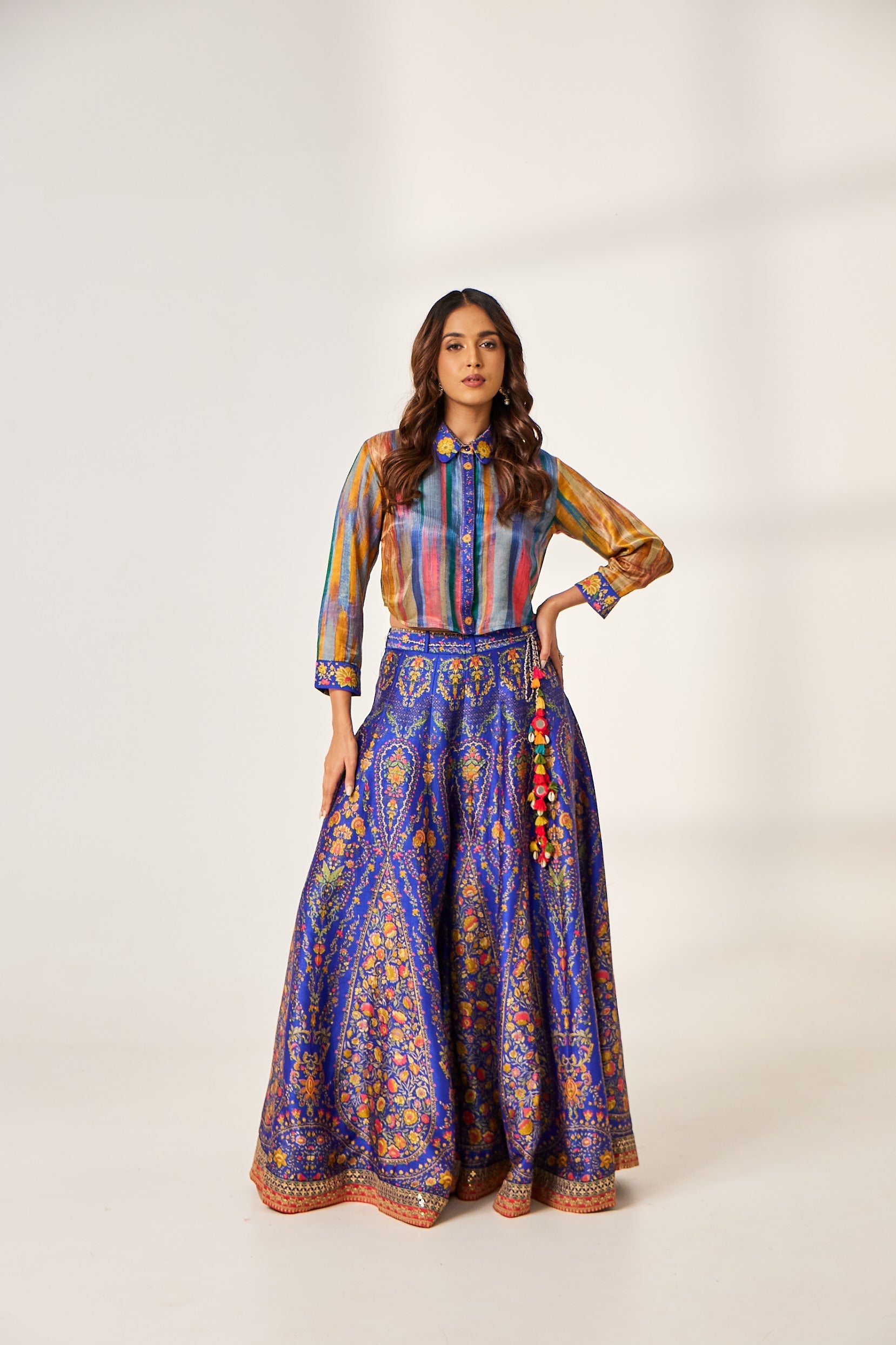 A woman poses in a silk co-ord set which includes a tasselled and backless Indo-Western tunic and broad border palazzo.