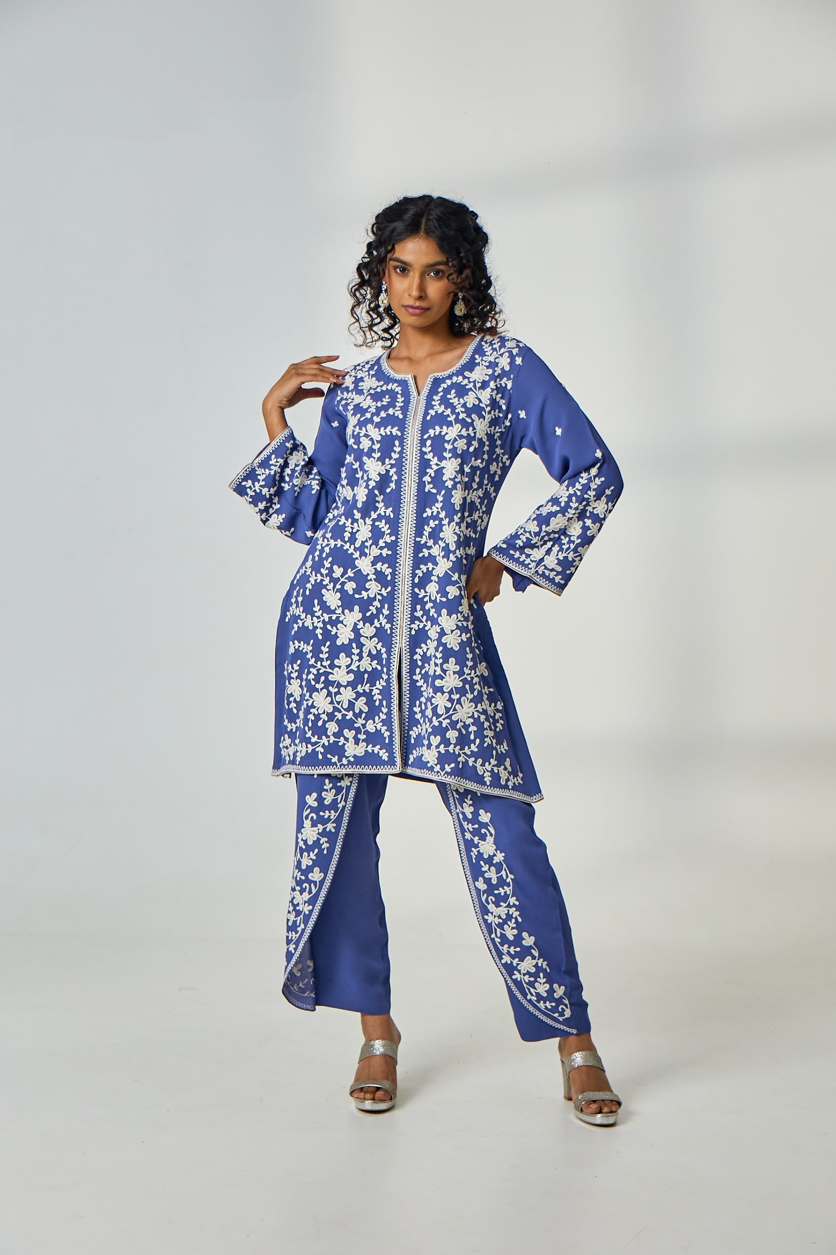 A woman poses in a cornflower blue crepe co-ord set featuring a kurta with intricate resham thread work, paired with elegant tulip-style dhoti pants.