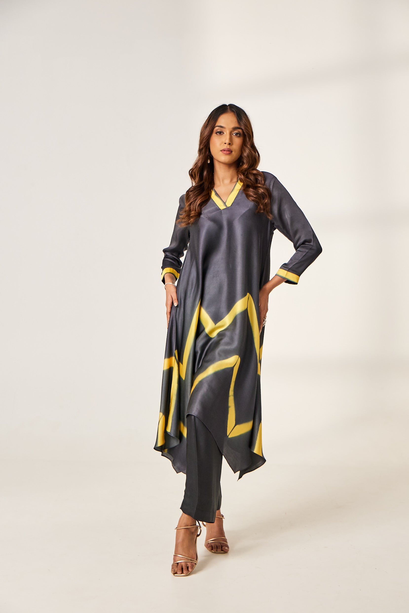 A woman poses in a black and yellow satin co-ord set which includes a V-neck tie-dyed kurti and a cotton-satin pant.