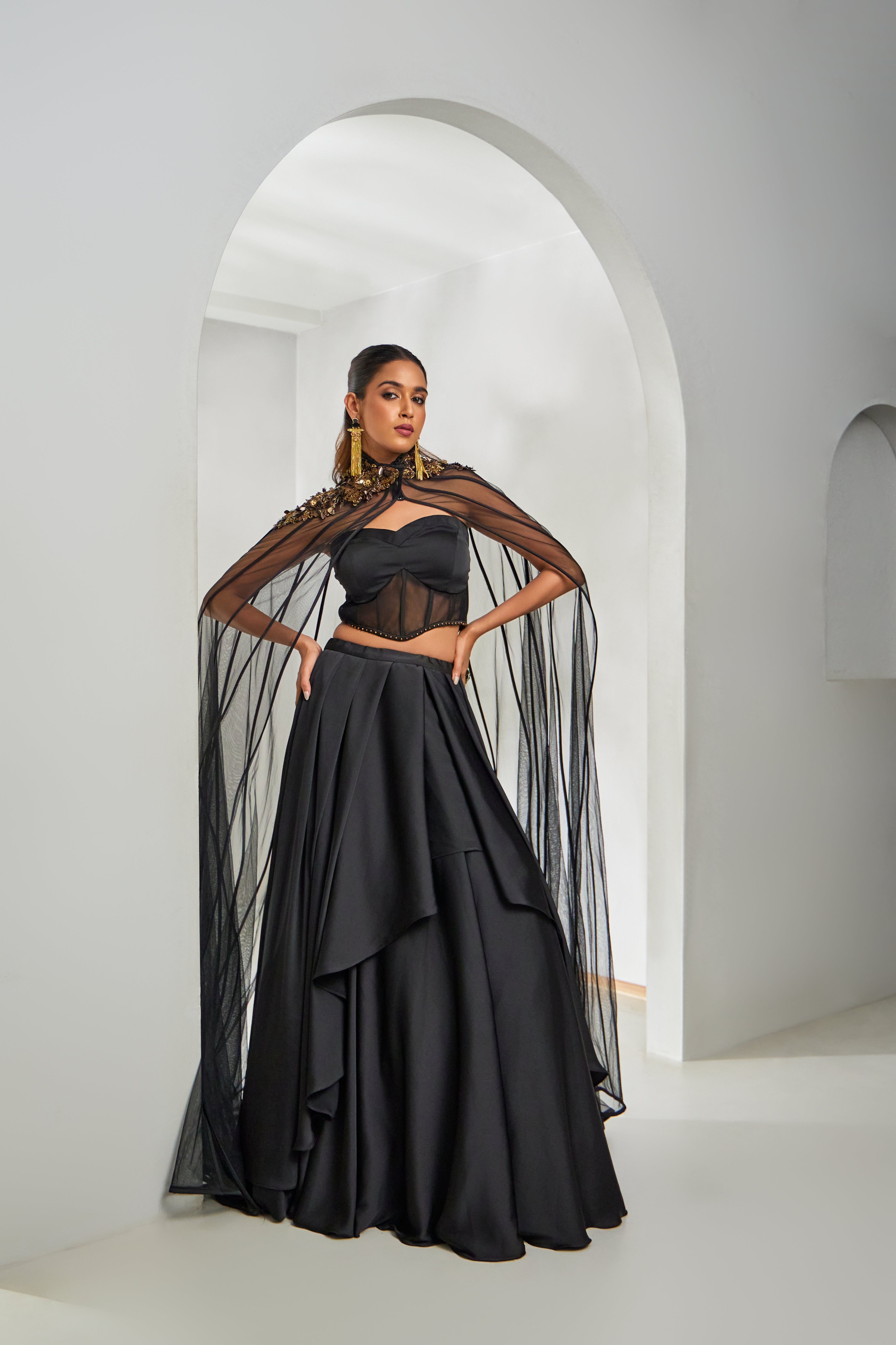 A striking black Indo-Western ensemble featuring a net cape with sequin, rambo-katdhana, and long bead work. Paired with a satin silk skirt and blouseâ€â€elegance with an edge.