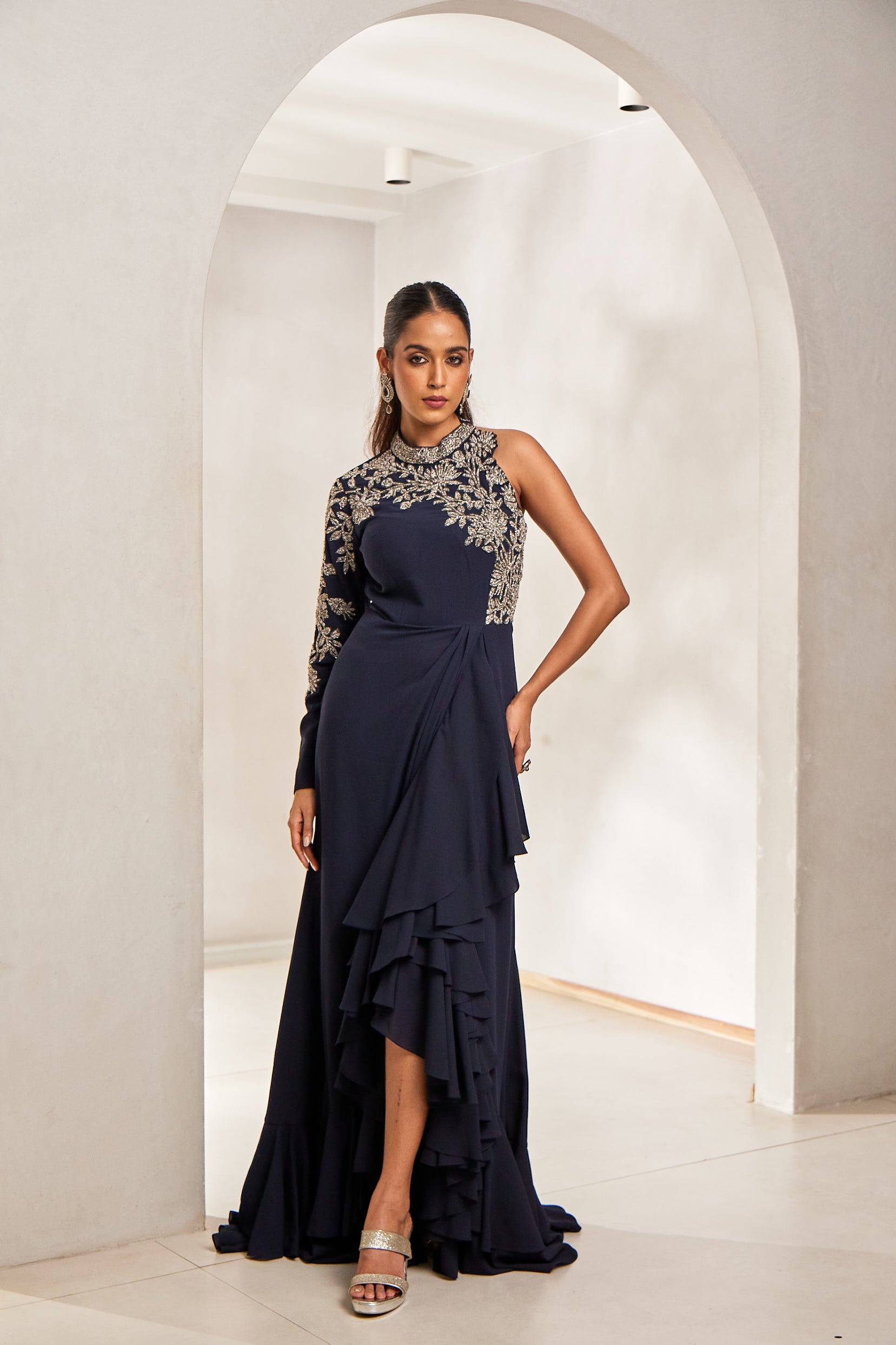 A woman makes a striking statement in a blue crepe-georgette Indo-Western gown. Embellished with katdana, sequins, pot, and long tube bead workâ€â€the look blends graceful movement with festive glamour.