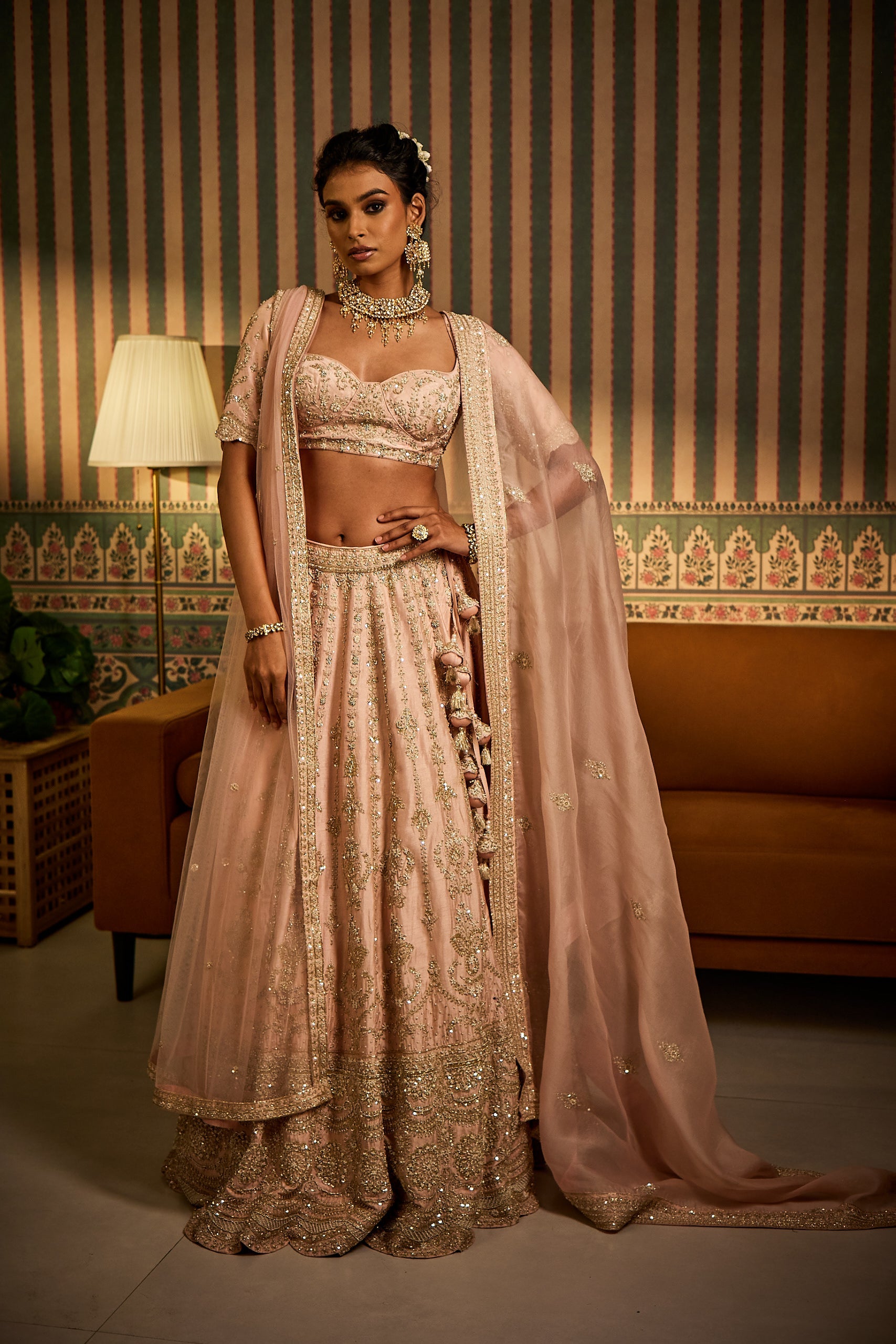 A bride glows in a powder pink silk bridal lehenga set, paired with an organza dupatta and a delicate net head dupatta. Intricately adorned with sequin, katdana, pot, zari, and zardosi workâ€â€crafted to make a statement on the big day.