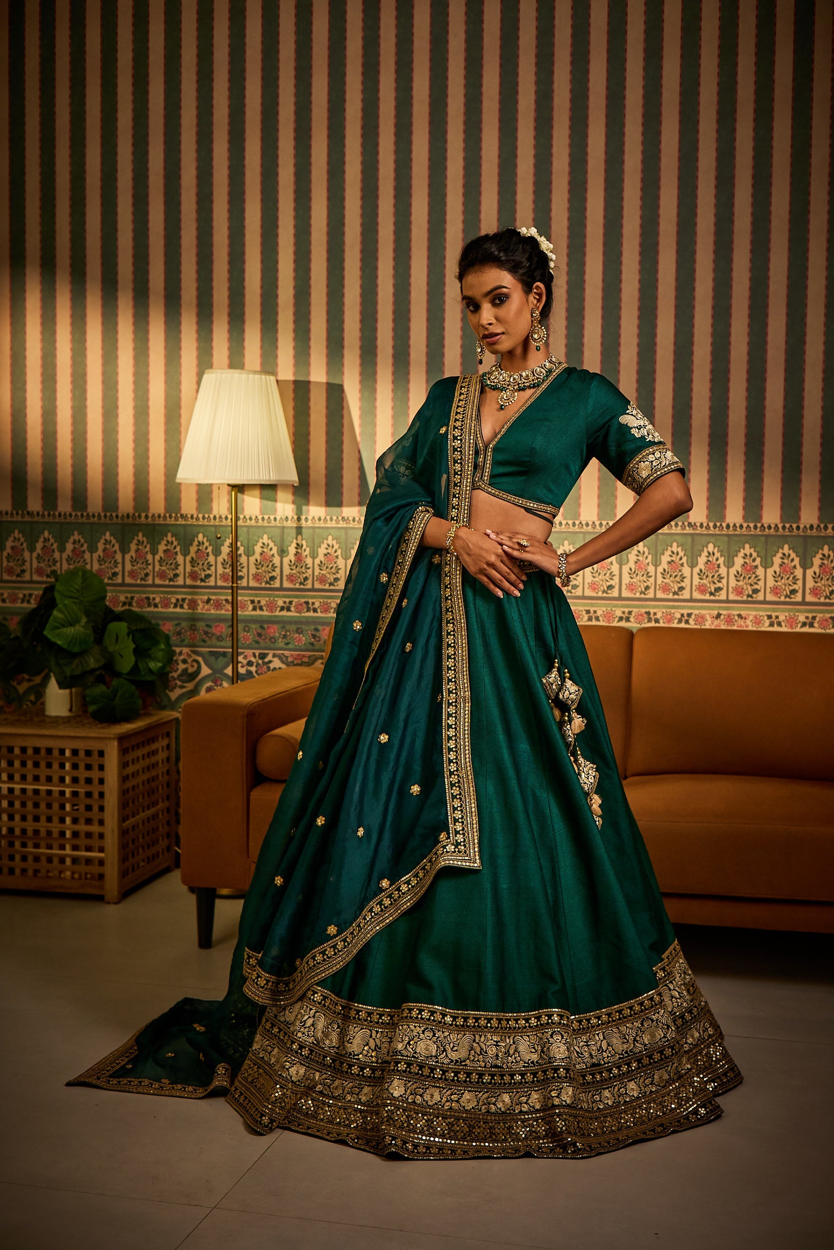 A woman enchants in a bottle green silk lehenga set, featuring a matching blouse and an airy organza dupatta. Accented with thread, dori, and sequin machine embroideryâ€â€an elegant choice for a bridesmaid’s celebration.