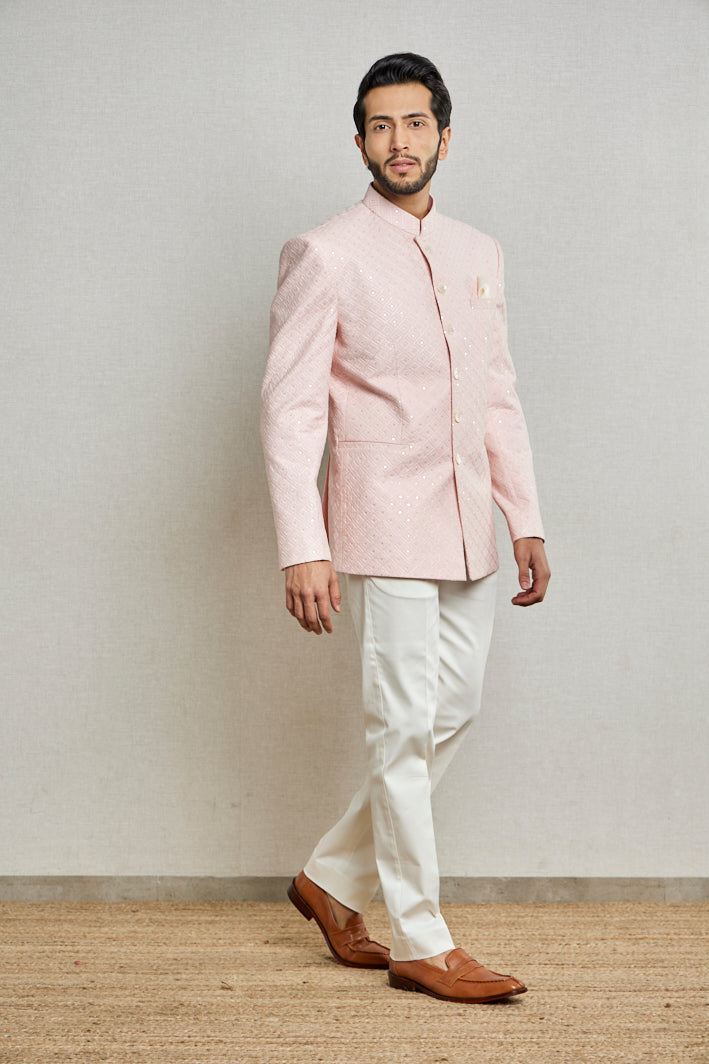 A man poses in a baby pink cotton silk bandgala from BenzerWorld ethnicwear store while standing in front of a wall.