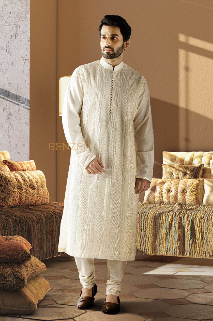 A man poses in a beige cotton silk embroidered kurta set from BenzerWorld ethnicwear store.