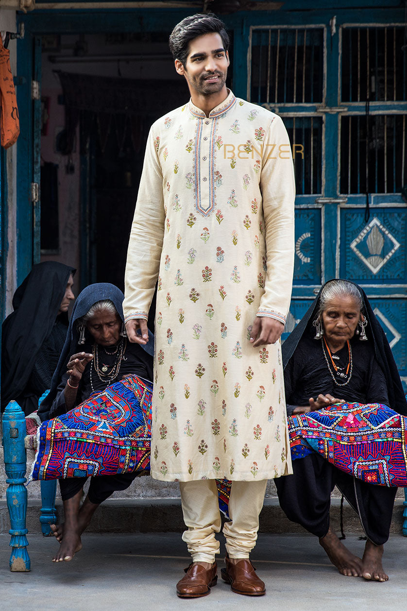 A man poses in a beige chanderi silk embroidered kurta set from BenzerWorld ethnicwear store.