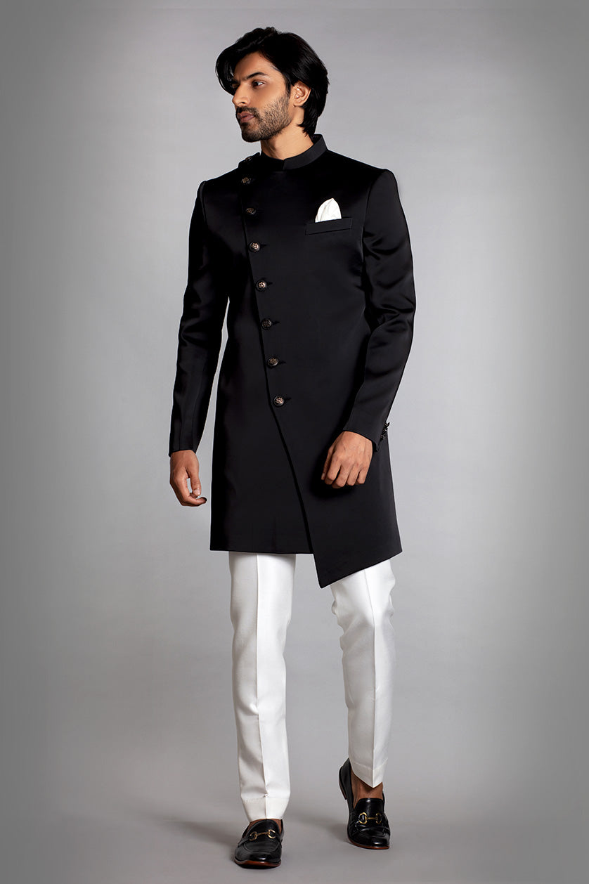 A man poses in a black micro-satin sangeet outfit from BenzerWorld ethnicwear store.