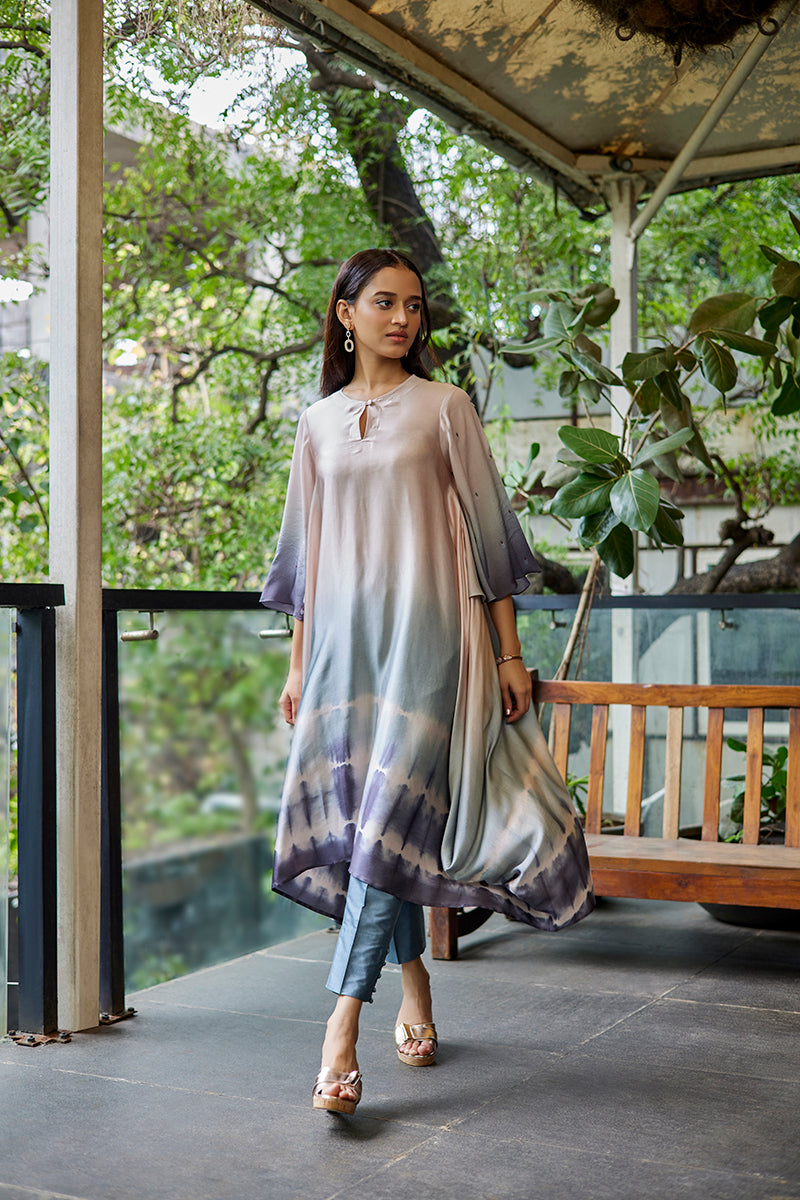 A woman poses in a champagne grey satin georgette kurti from BenzerWorld ethnicwear store, while walking.