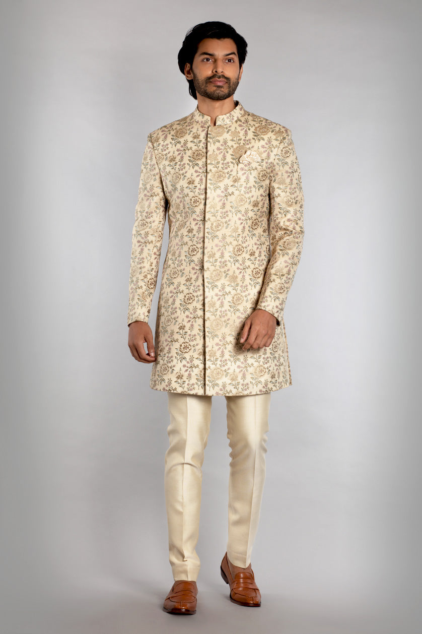 A man poses in a cream silk sangeet outfit from BenzerWorld ethnicwear store.