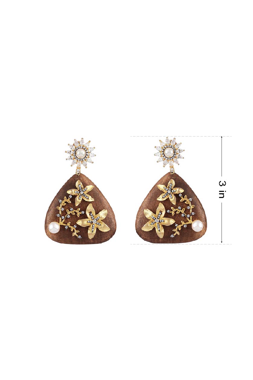 A closeup of earrings with gold plated flowers on wood from BenzerWorld ethnicwear store.