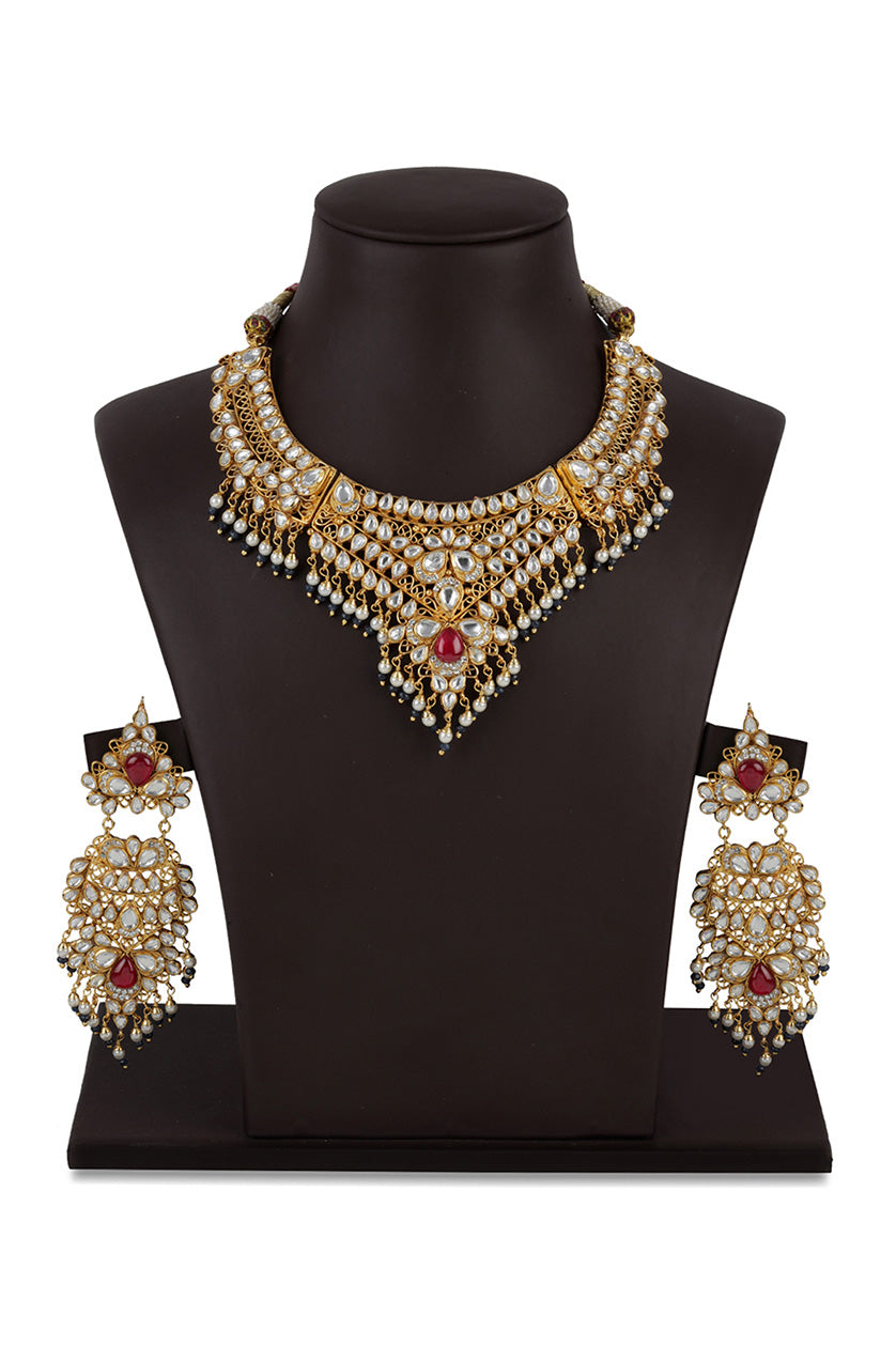 A closeup of a gold plated kundan set with maroon stone from BenzerWorld ethnicwear store.