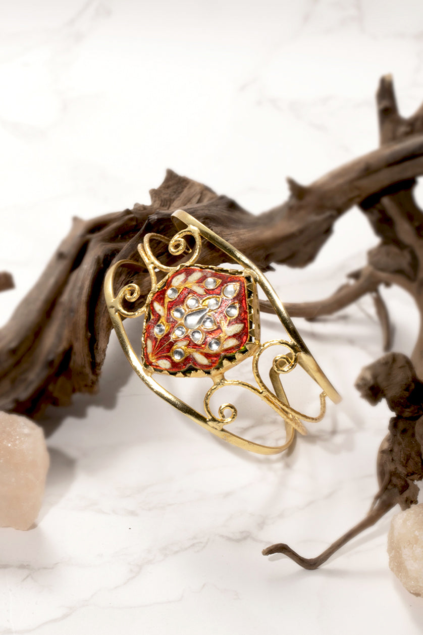 A closeup of a gold polished hand cuff from BenzerWorld ethnicwear store.