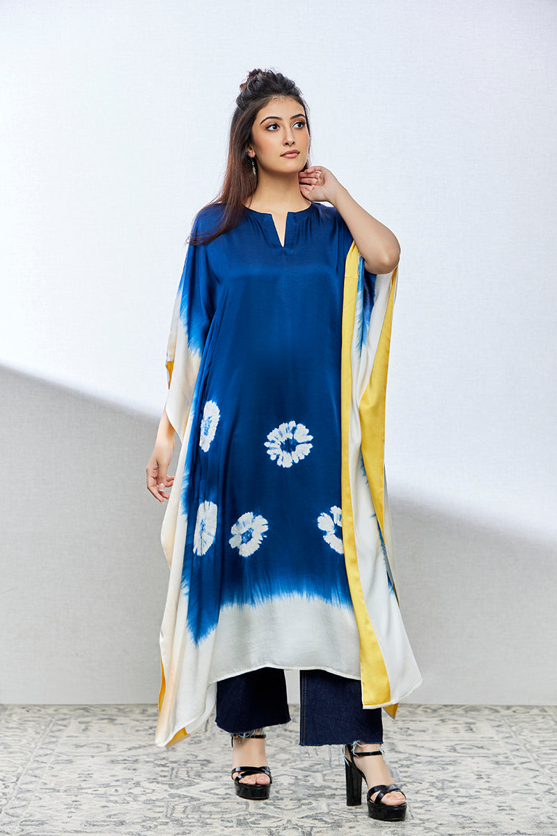 A woman poses in an indigo tie-dyed satin silk kurti from BenzerWorld ethnicwear store, while smiling.