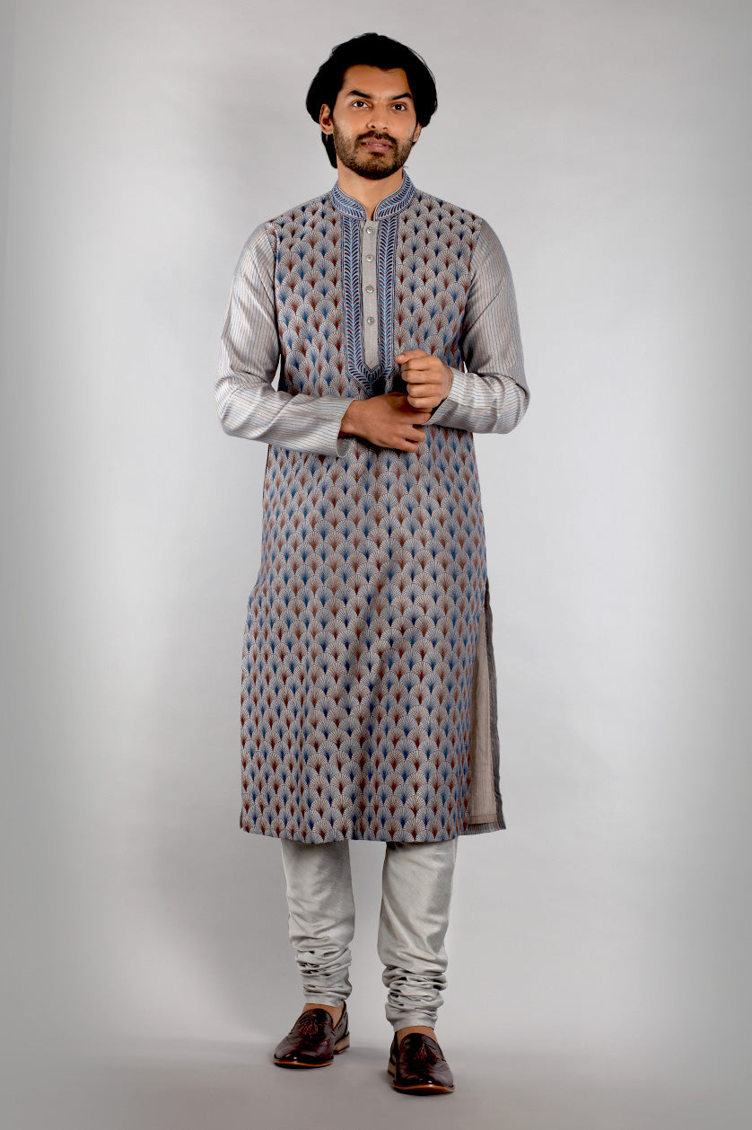 A man poses in a light grey cotton silk embroidered kurta set from BenzerWorld ethnicwear store.