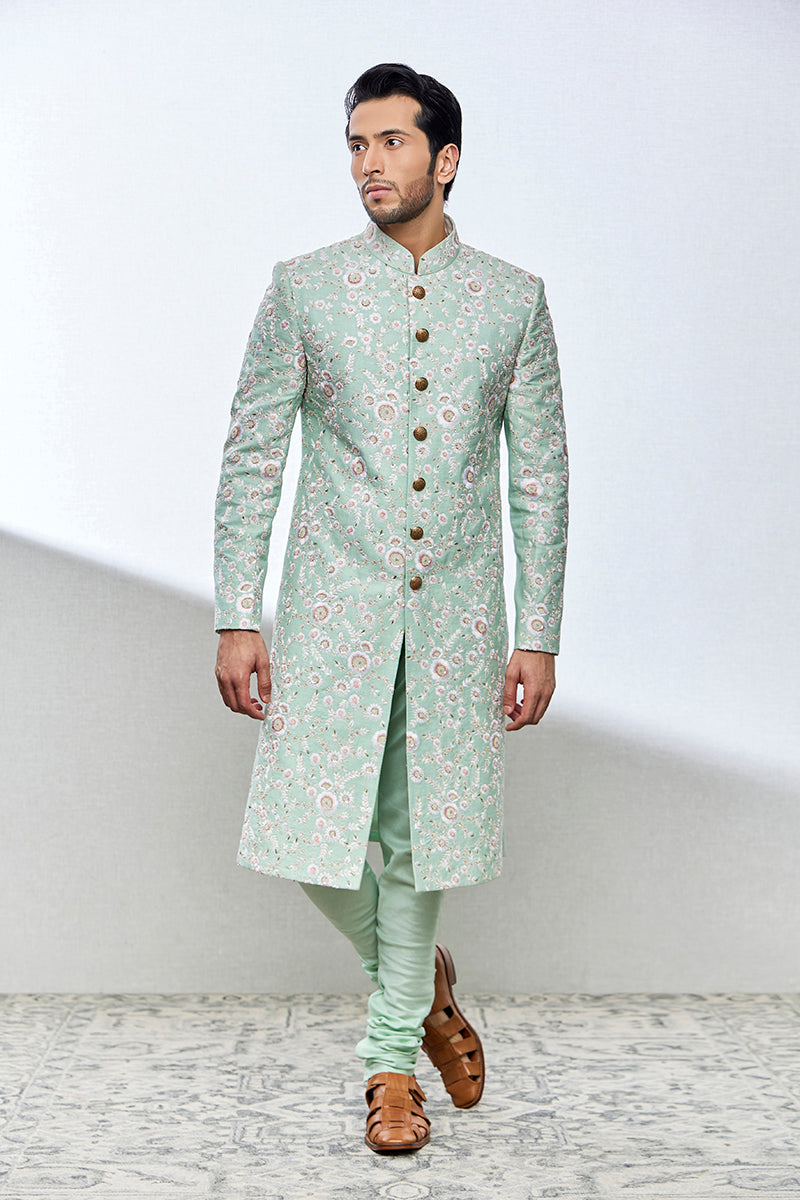 A man poses in a mint green sherwani from BenzerWorld ethnicwear store.