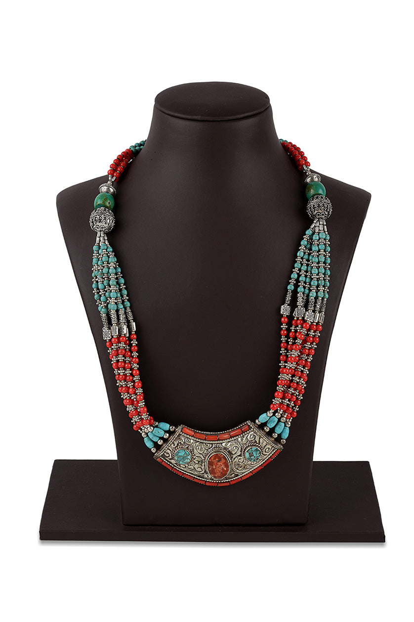 A closeup of a multicoloured necklace with a crescent pendant from BenzerWorld ethnicwear store.