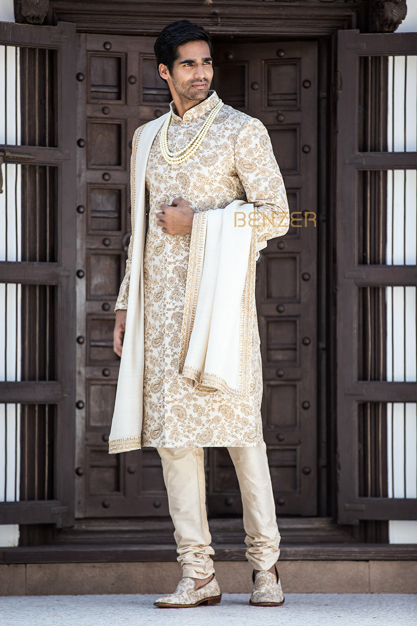 A man poses in a pearl white silk groom's sherwani from BenzerWorld ethnicwear store.