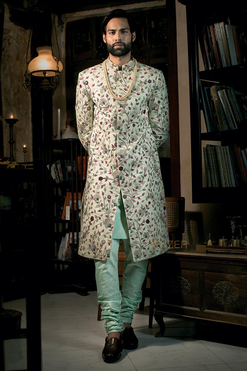 A man poses in a pista green raw silk groom's sherwani from BenzerWorld ethnicwear store.