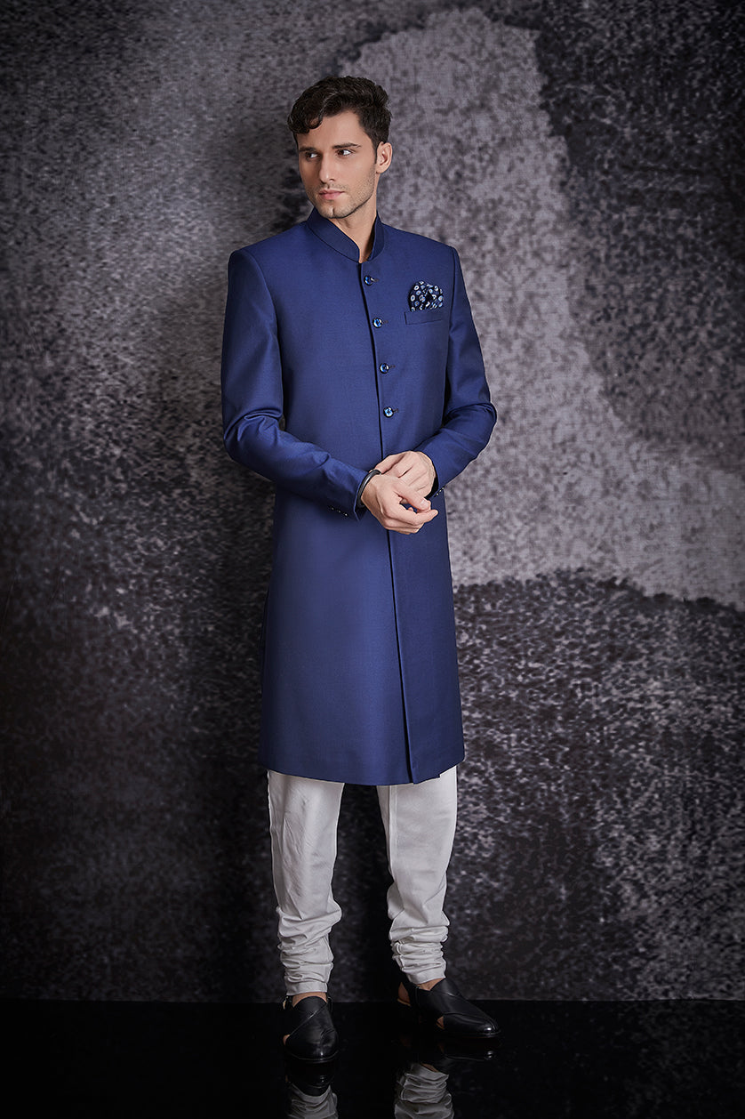 A man poses in a royal blue terrywool nawabi sherwani from BenzerWorld ethnicwear store.