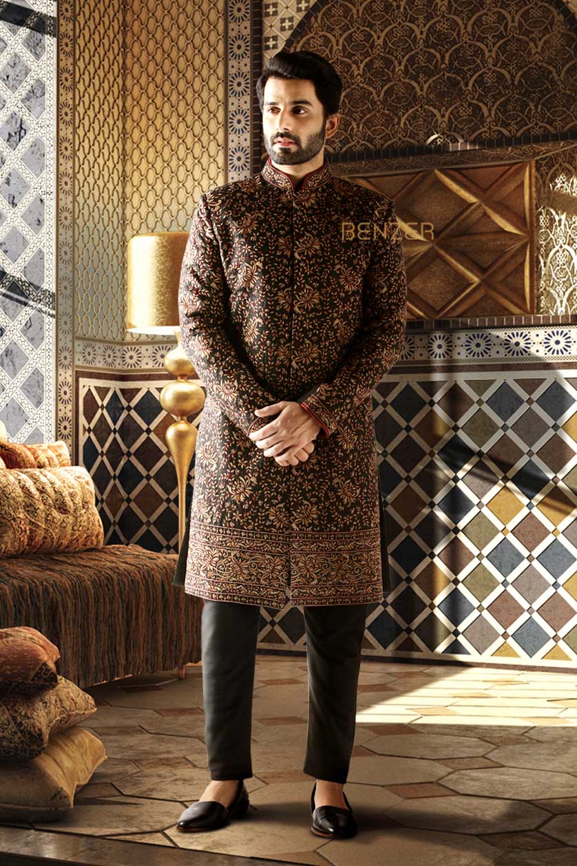 A man poses in a black raw silk groom's sherwani from BenzerWorld ethnicwear store.
