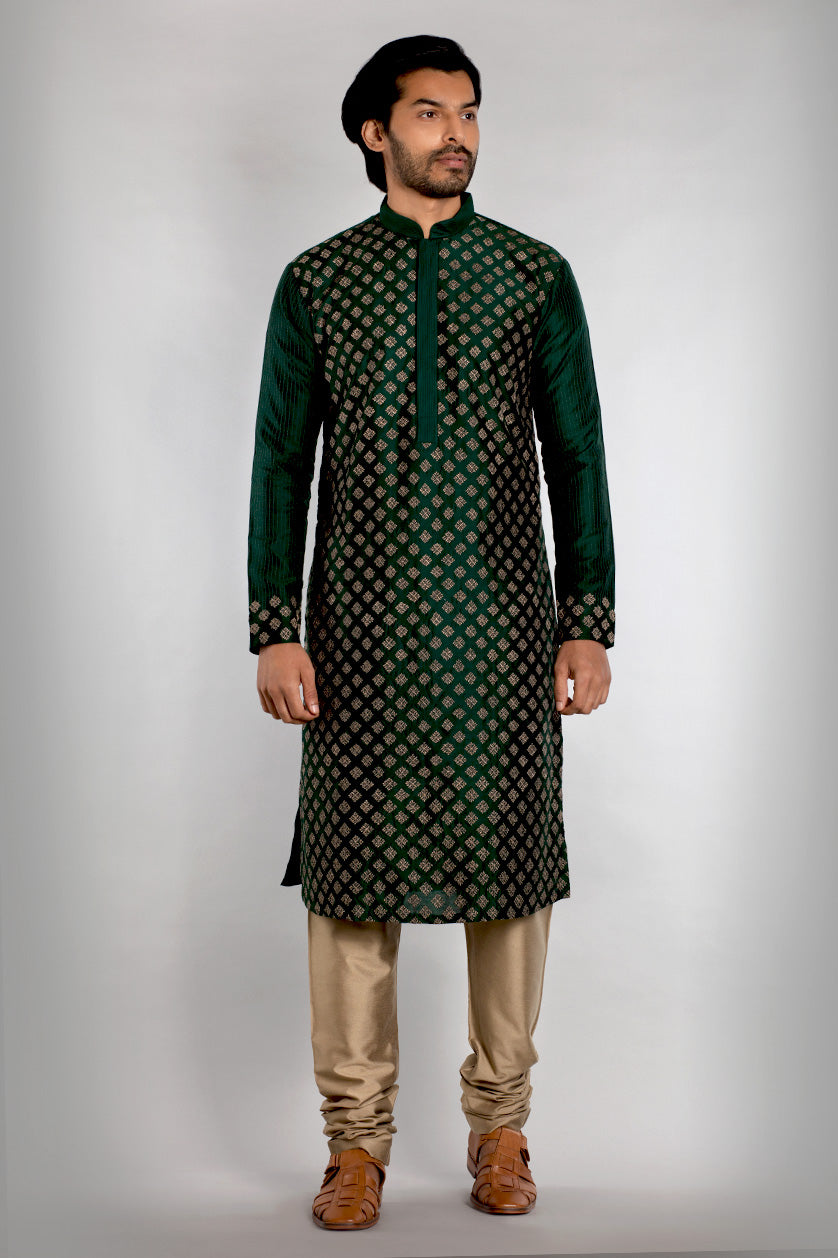 A man poses in a bottle green cotton silk embroidered kurta set from BenzerWorld ethnicwear store.