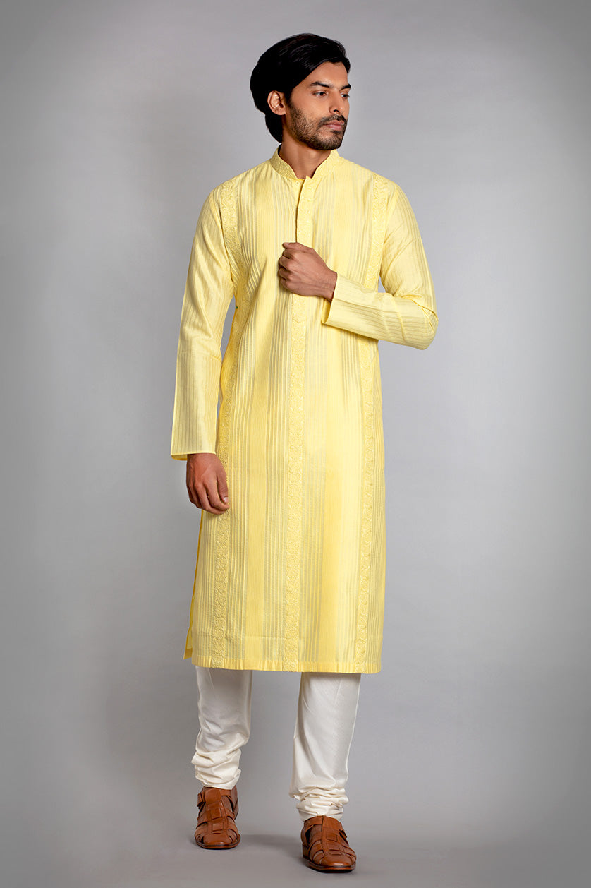 A man poses in a pastel yellow cotton silk embroidered kurta set from BenzerWorld ethnicwear store.