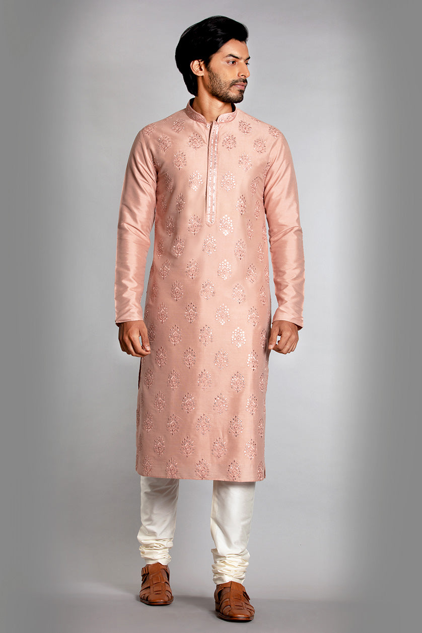 A man poses in a peach cotton silk embroidered kurta set from BenzerWorld ethnicwear store.