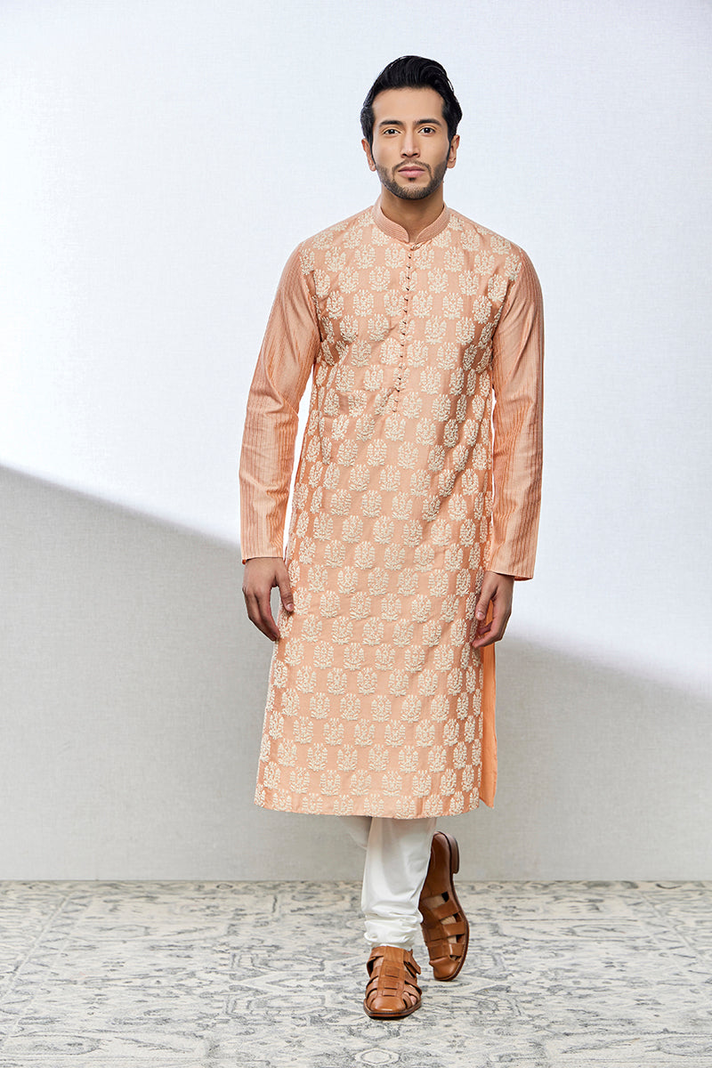 A man poses in a peach cotton silk kurta set from BenzerWorld ethnicwear store.