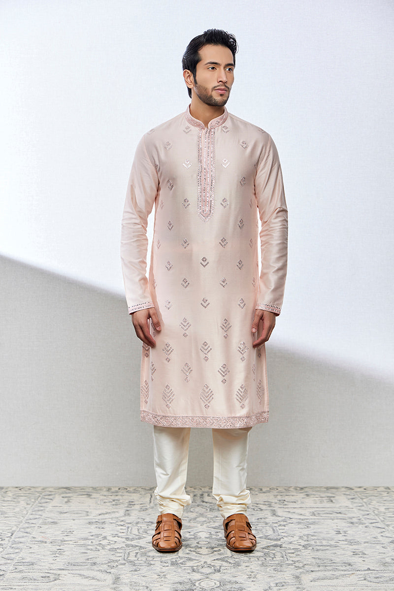 A man poses in a powder pink cotton silk kurta set from BenzerWorld ethnicwear store.