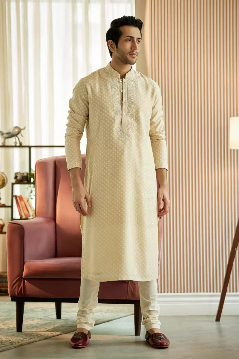 A man in a beige chanderi silk kurta set from BenzerWorld ethnicwear store poses for the camera.